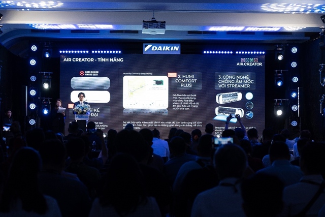 A group of people in front of a large screenDescription automatically generated